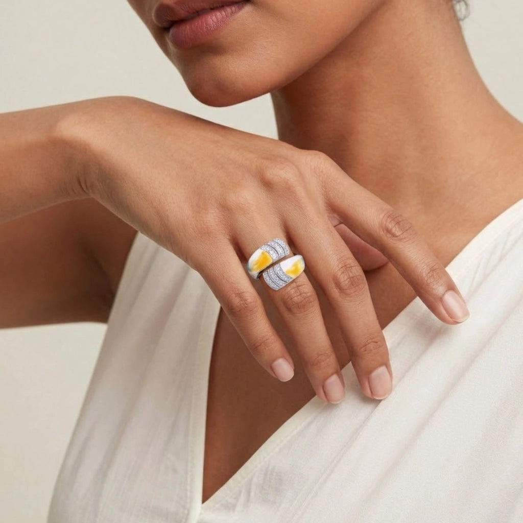 Close-up of a woman's hand wearing a silver ring with yellow gemstones on a neutral background