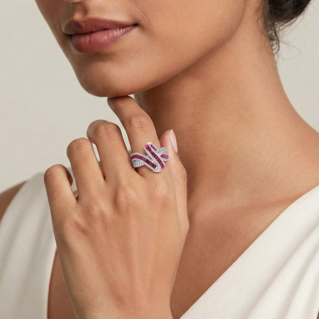 Close-up of a woman's hand wearing a decorative ring with pink gemstones on a neutral background