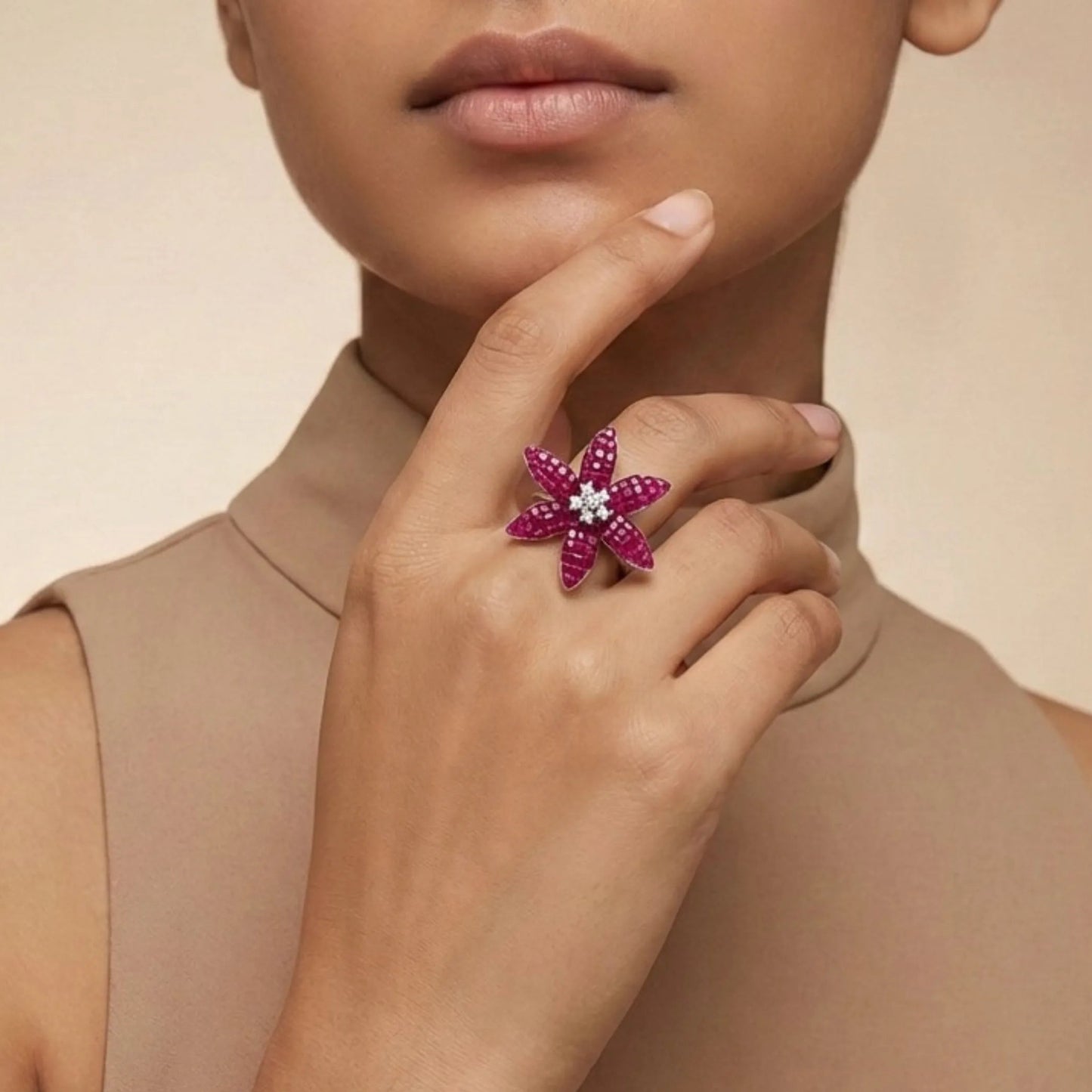 Woman wearing a pink flower-shaped ring on a beige background