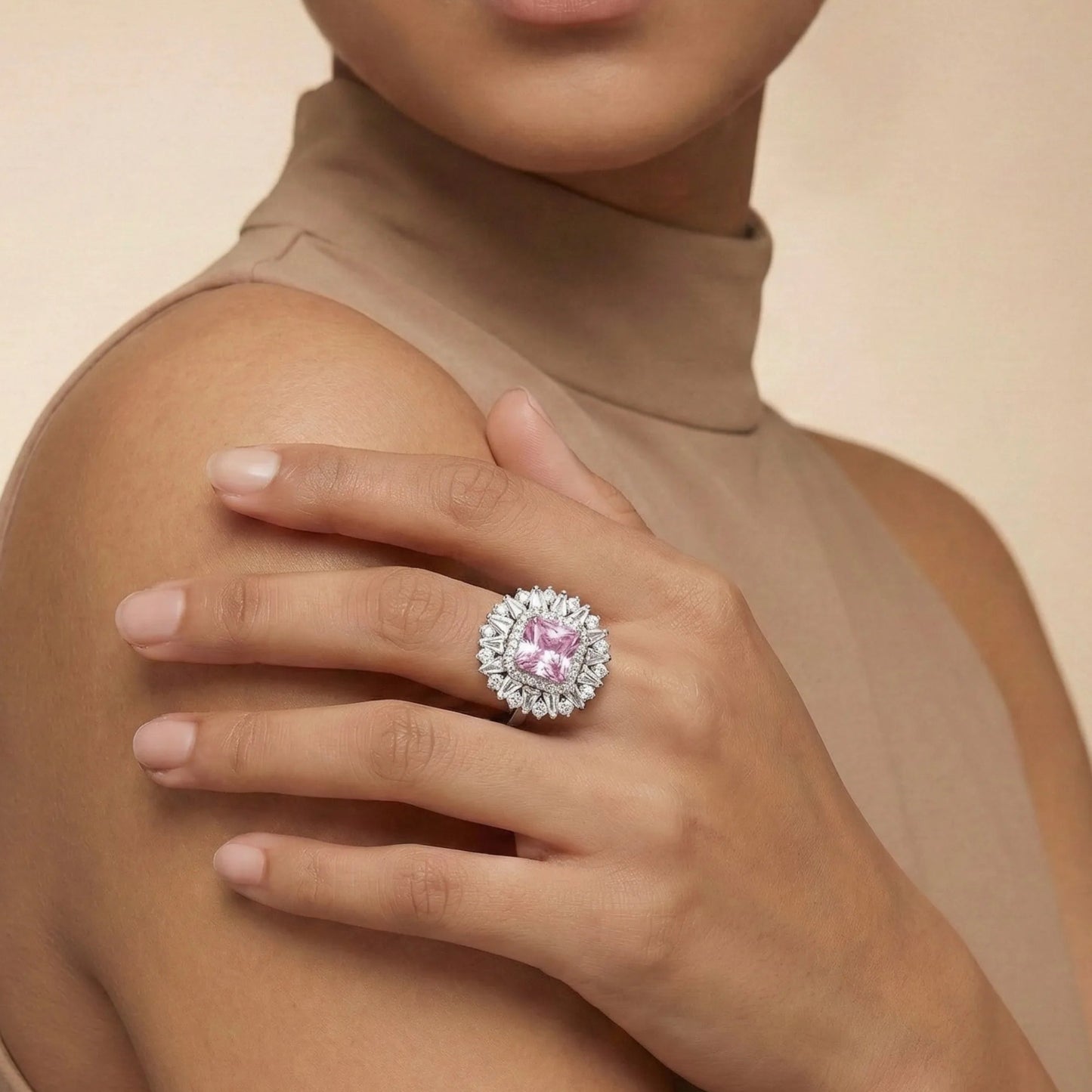 Woman wearing a ring with a pink gemstone on a beige background