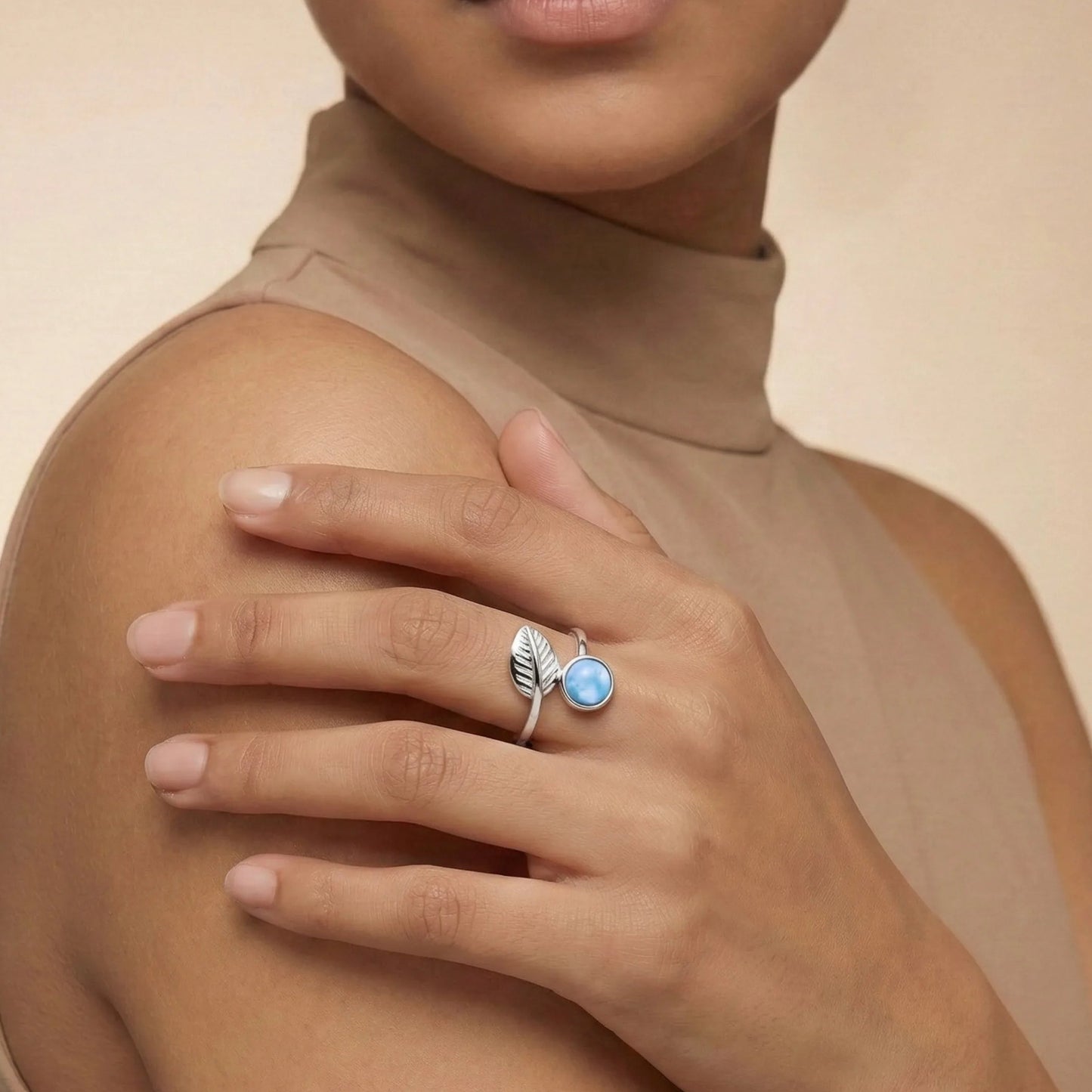 Woman wearing a Larimar Leaf Ring on a beige background