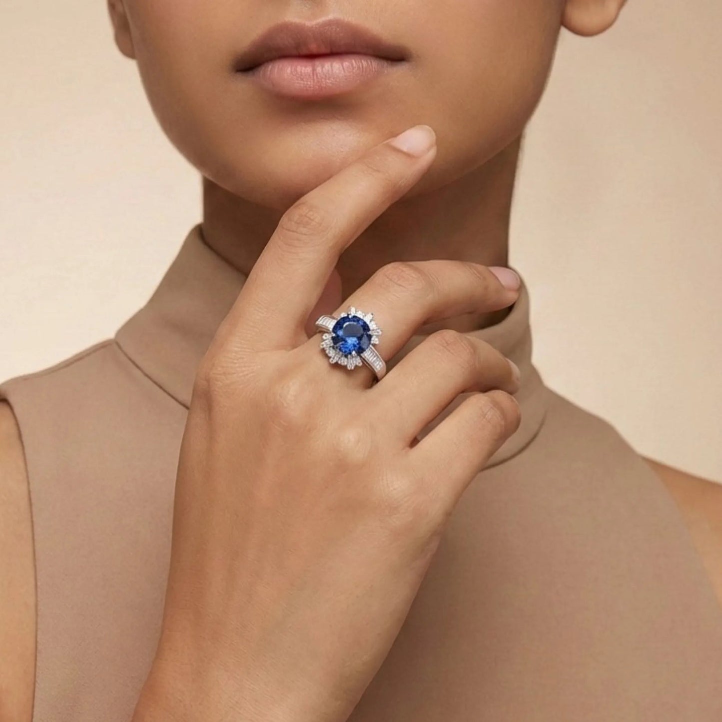 Woman wearing a ring with a blue gemstone on a beige background