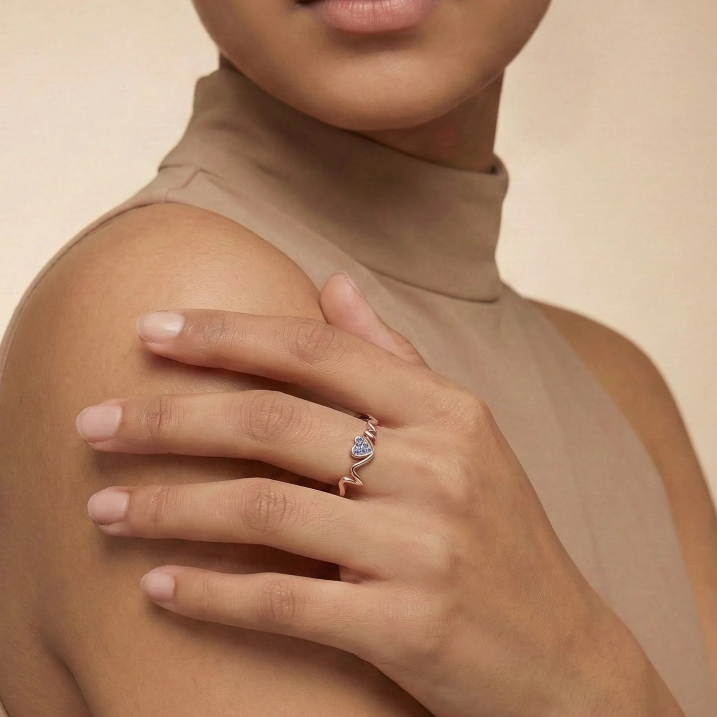 Woman wearing a Heartbeat Rose Gold Ring on a beige background