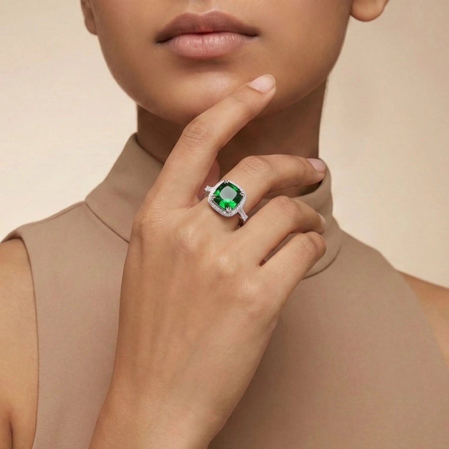 Woman wearing aEmerald Cushion Halo Ring on a beige background