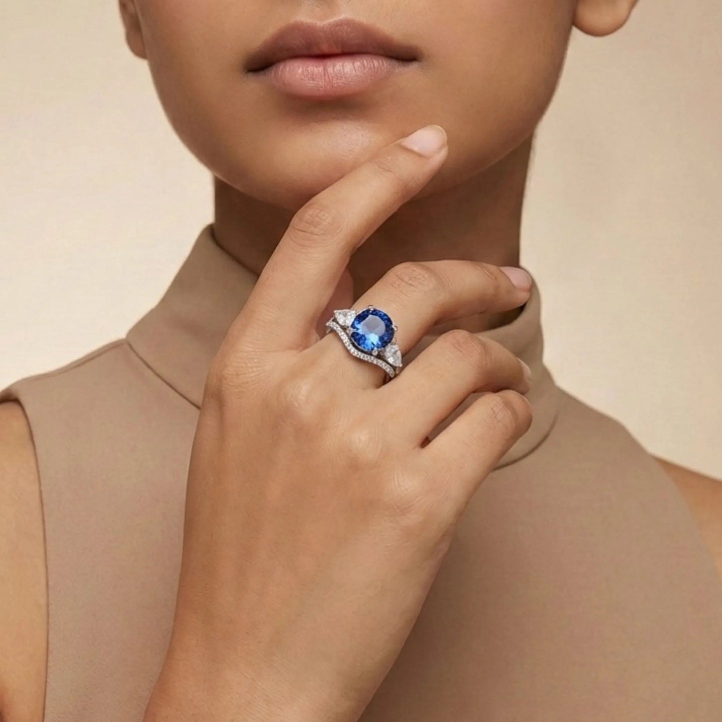 Woman wearing a Blue Sapphire Trilogy Ring on a beige background